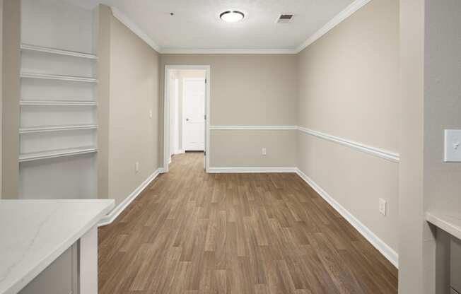 an empty room with wooden floors and white shelves