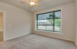 an empty living room with a large window and a ceiling fan at The Augustan, Augusta