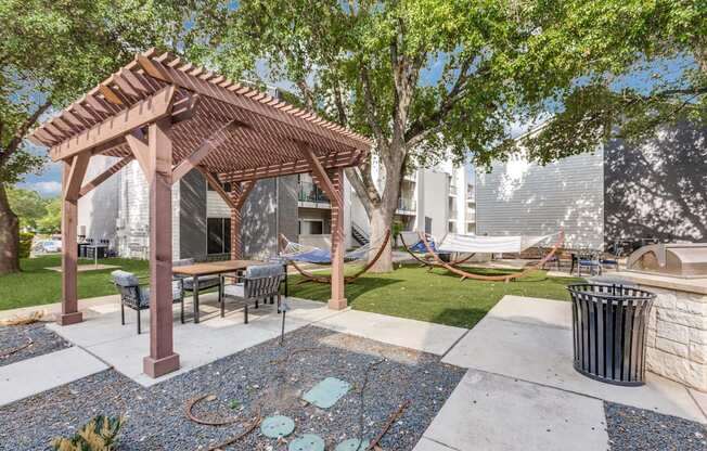A patio with a table and chairs under a pergola.