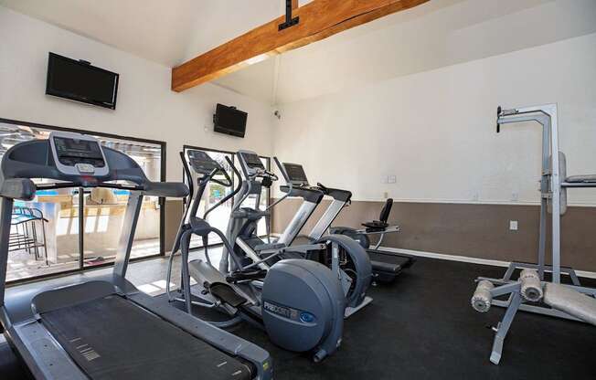 A gym with treadmills, exercise bikes, and a television.
