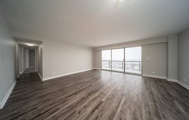 an empty living room with wood flooring and a large window