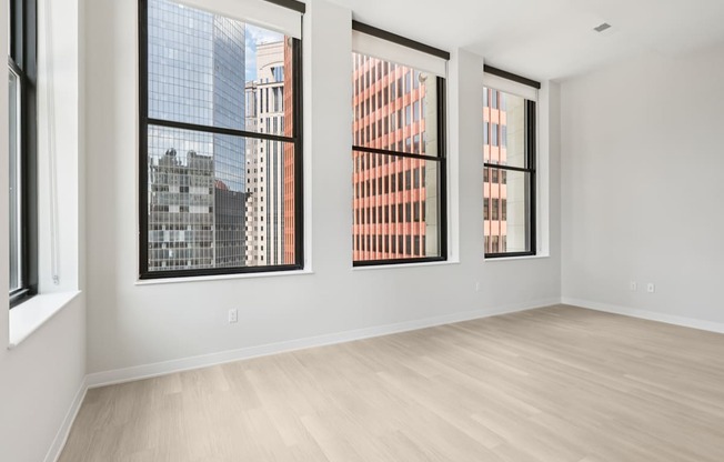 Three windows in a white room with wooden floors.