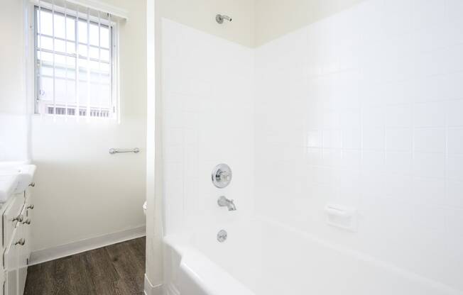 a white bathroom with a tub and a window