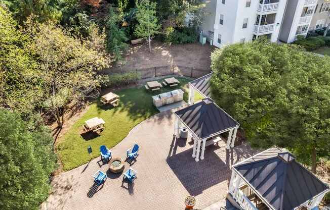 A bird's eye view of a backyard with a gazebo, lawn chairs, and a fire pit.