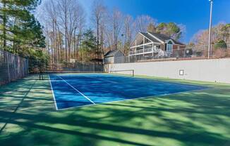 a tennis court with a house in the background