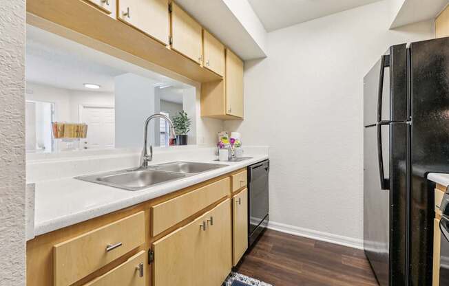 A kitchen with wooden cabinets and a black refrigerator.
