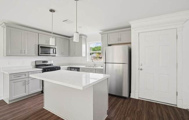 A kitchen with a white island and stainless steel appliances.