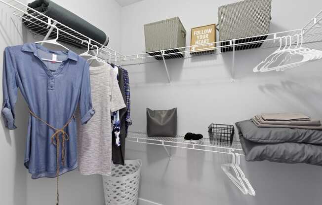 a walk in closet with a rack of clothes and a bed in it