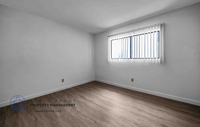 the upstairs bedroom with hardwood floors and a large window