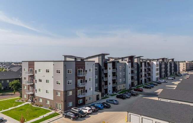 A row of apartment buildings with cars parked in the driveways.