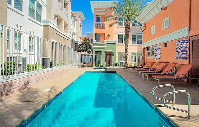 A swimming pool surrounded by a metal fence and chairs.