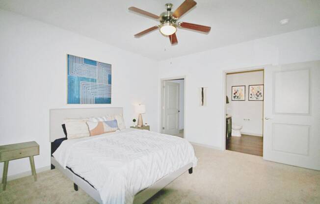 a bedroom with a large white bed and a ceiling fan
