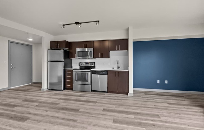 A kitchen with a blue wall and wooden floors.