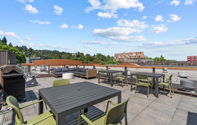 a rooftop patio with tables and chairs and a city in the background