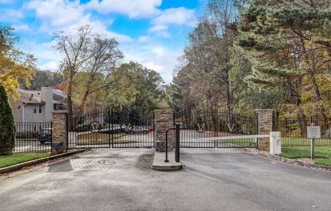 the gate at the end of a driveway with a house behind it