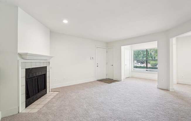 A spacious living room with a fireplace and carpeted floor.