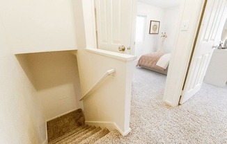 a hallway with a staircase and a bedroom with a bed