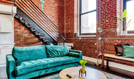 a living room with a green couch and a brick wall