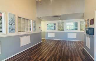A room with wooden floors and a black rug in the foreground.