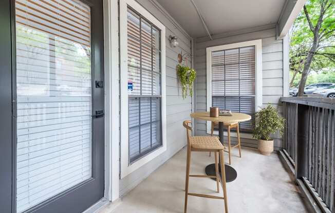 a small table and chair sit on a porch in front of a door at Carmel at Deerfield, Texas, 78248