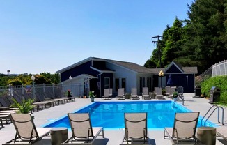 a swimming pool with deck chairs and a building in the background