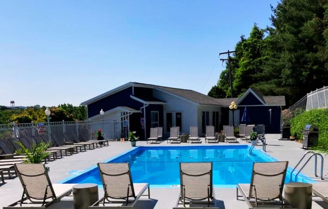 a swimming pool with deck chairs and a building in the background