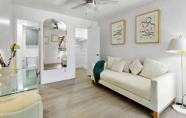 A living room with a white couch and a glass table.