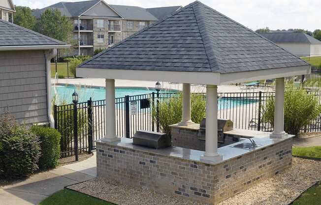 A gazebo with a hot tub sits in a backyard.