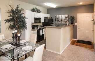 A modern kitchen with a glass table set for two.
