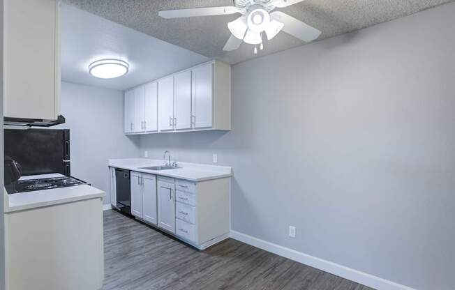 A kitchen with white cabinets and a black fridge.