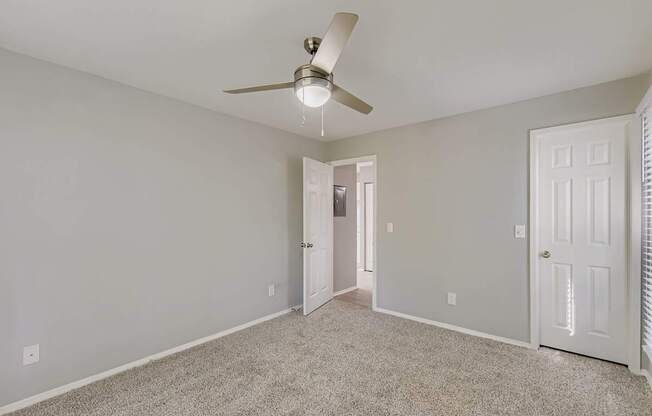 A room with a ceiling fan and carpeted floor.