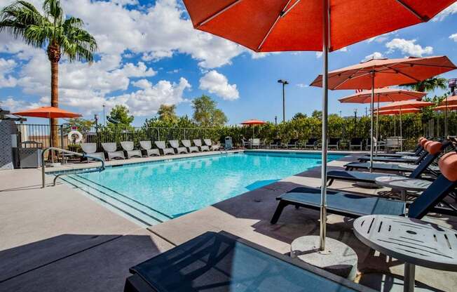 Colton Apartments A pool surrounded by sun loungers and umbrellas.