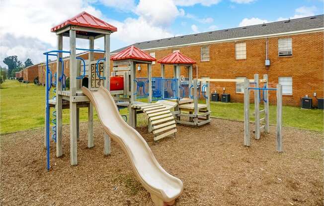 a playground with a slide and chairs in front of a building