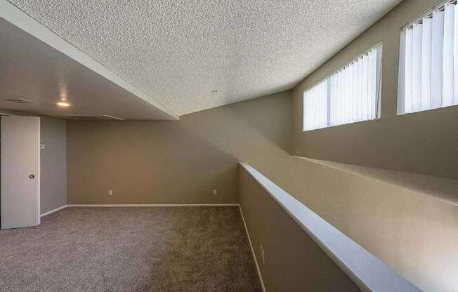 A room with a carpeted floor and a window with blinds.