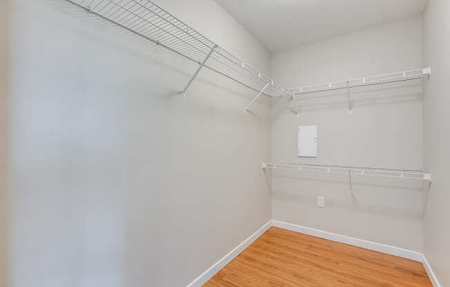 an empty room with white walls and wood flooring and a closet