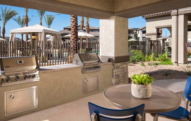 a patio with two bbq grills and a table with chairs