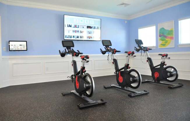 Three stationary bikes are lined up in a room.