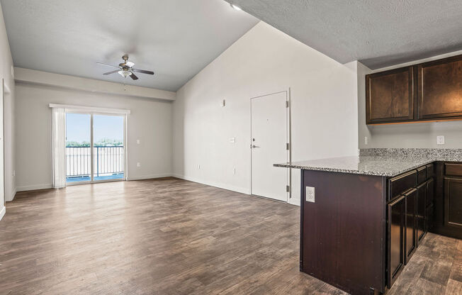 an empty living room and kitchen with a door to a balcony