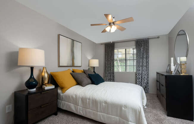 A bedroom with a bed, nightstands, and a ceiling fan.