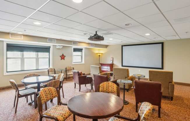 a conference room with tables and chairs and a projection screen