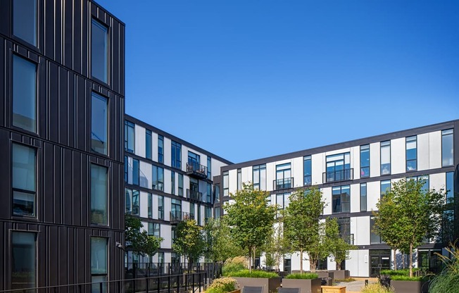 a rendering of a courtyard with tables and chairs in front of buildings