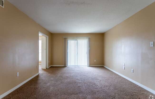 the spacious living room of an empty house with a large window