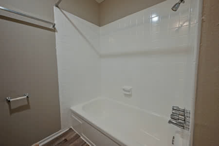 A white bathtub in a bathroom with a white shower curtain.
