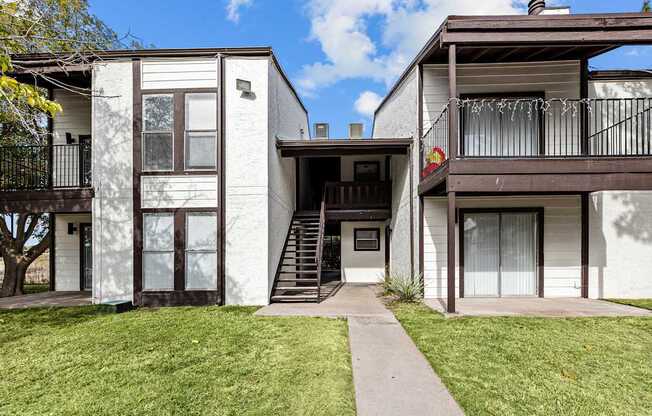 A white two-story house with a balcony on the upper floor.