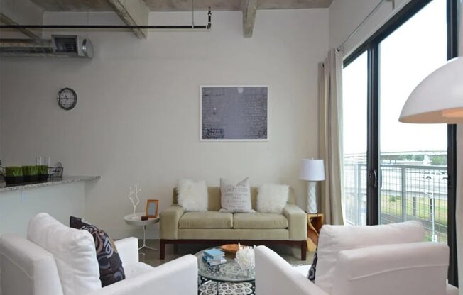 a living room with white furniture and a large window