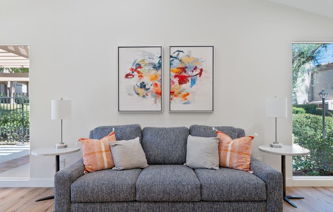 a living room with a couch and two paintings on the wall
