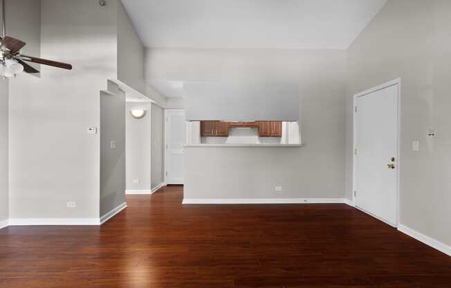 an empty living room with wood floors and a ceiling fan