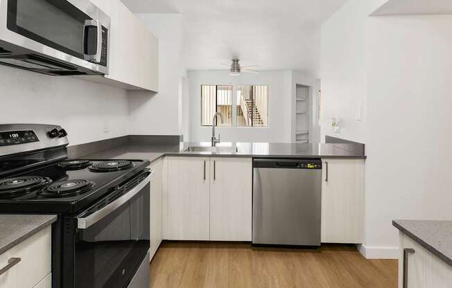A modern kitchen with a black stove top oven and white cabinets.