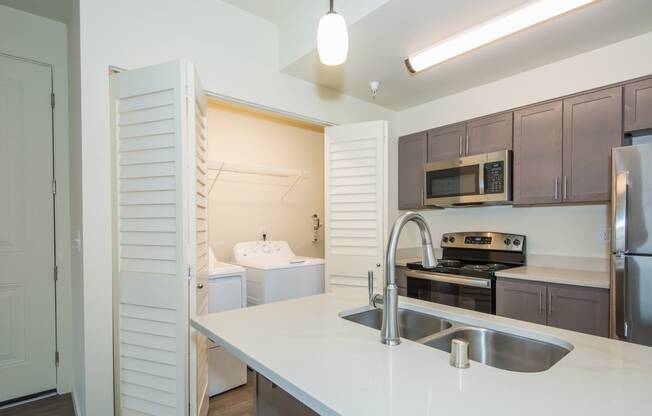 a kitchen with white counter tops and a stainless steel sink