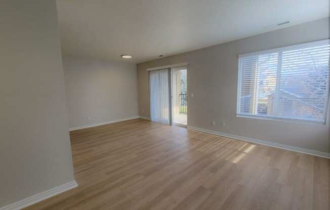 an empty living room with wood floors and a window